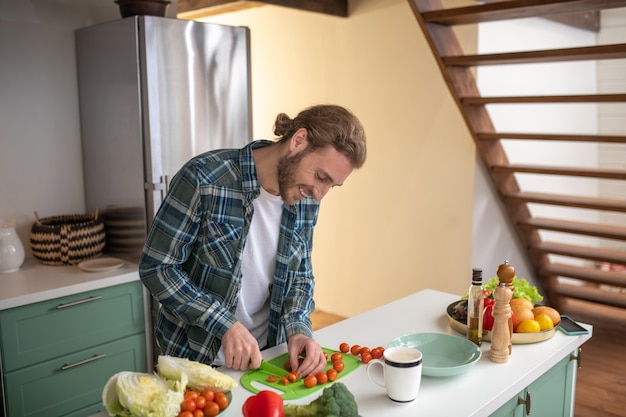 Een glimlachende man cherry tomaten snijden voor een salade