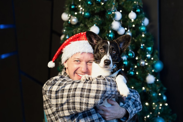 Een glimlachende man houdt een rasechte hond in zijn armen Welsh Corgi Pembroke Kerstvakantie en evenementen