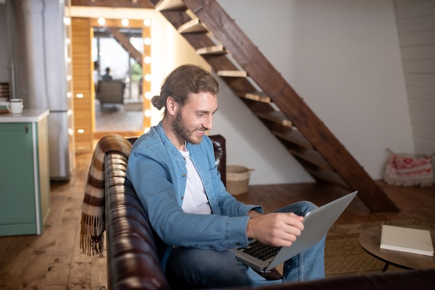 Een glimlachende man met zijn laptop thuis