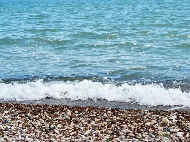 Een golf rolt over de kiezelstrand