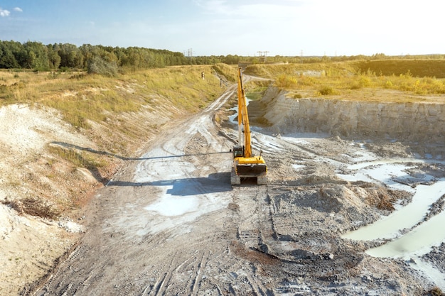 Een graafmachine op een bouwplaats plant de grond voordat hij aan de fundering gaat werken