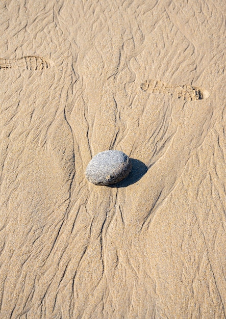 Een granieten rots op een golvend zandstrand Kopieer de ruimte