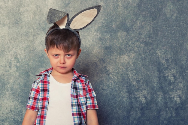 Een grappige knorrige kleine jongen heeft konijnenoren op zijn hoofd Kopieer de ruimte