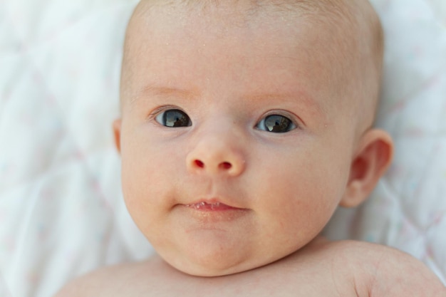 een grappige pasgeboren baby van twee maanden lacht zijn eerste glimlach