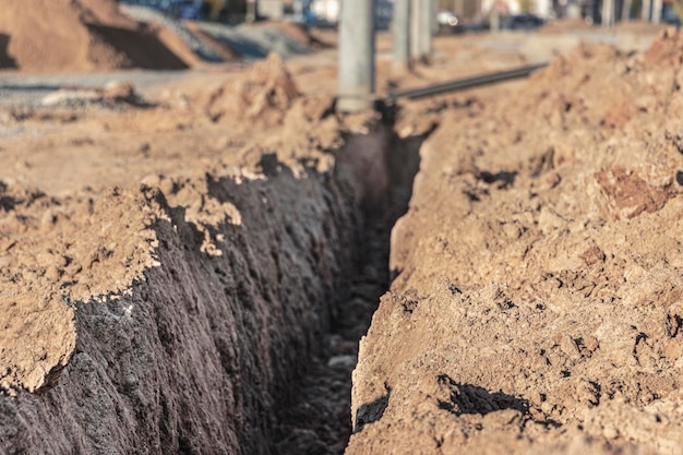 Een greppel in de grond voorbereid voor het leggen van de elektrische kabel op de bouwplaats.