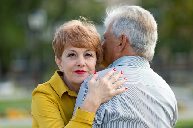 Een grijsharige man met zijn vrouw in het park