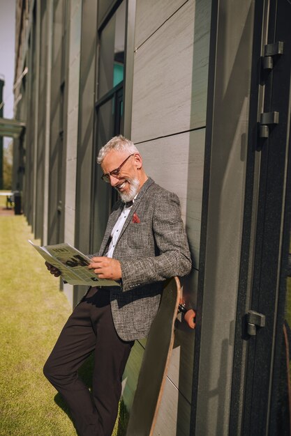 Een grijsharige zakenman die een krant leest en er betrokken uitziet