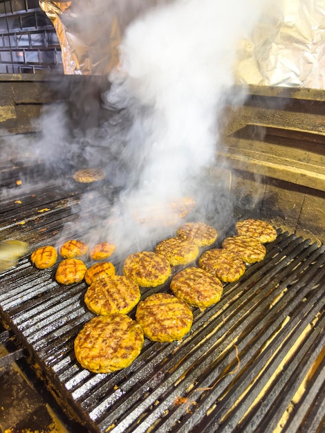 Een grill met hamburgers erop en er komt rook uit.