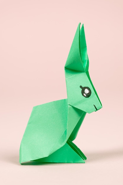 Een groen origamikonijn op een beige achtergrond