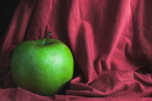 Een groene appel op een rode doekachtergrond