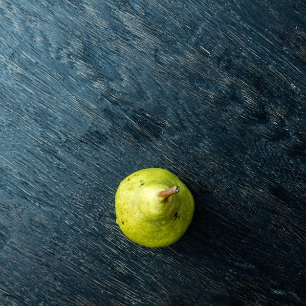 Een groene peer op een donkere ondergrond