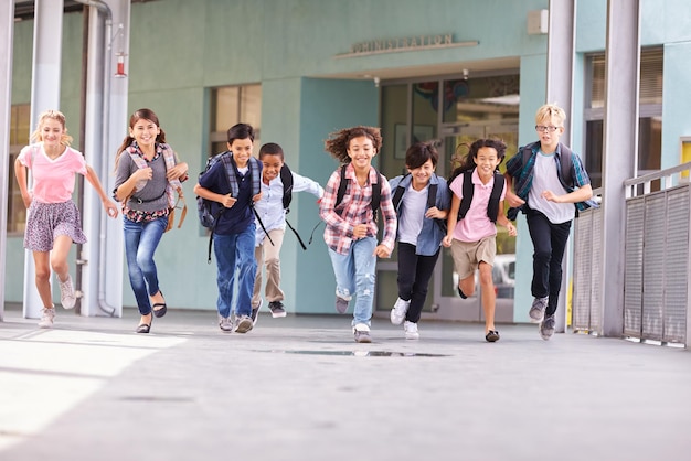 Een groep basisschoolkinderen die in een schoolcorridor rennen.