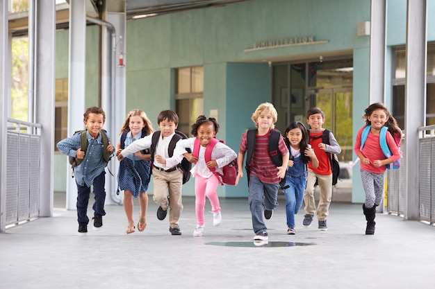Een groep basisschoolkinderen die in een schoolcorridor rennen.