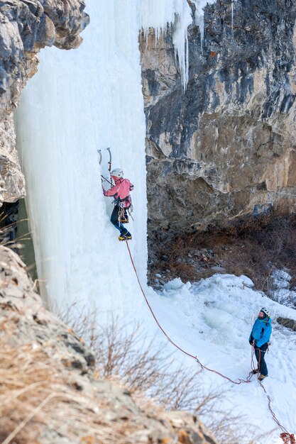 Een groep bergbeklimmers die een bevroren waterval beklimmen