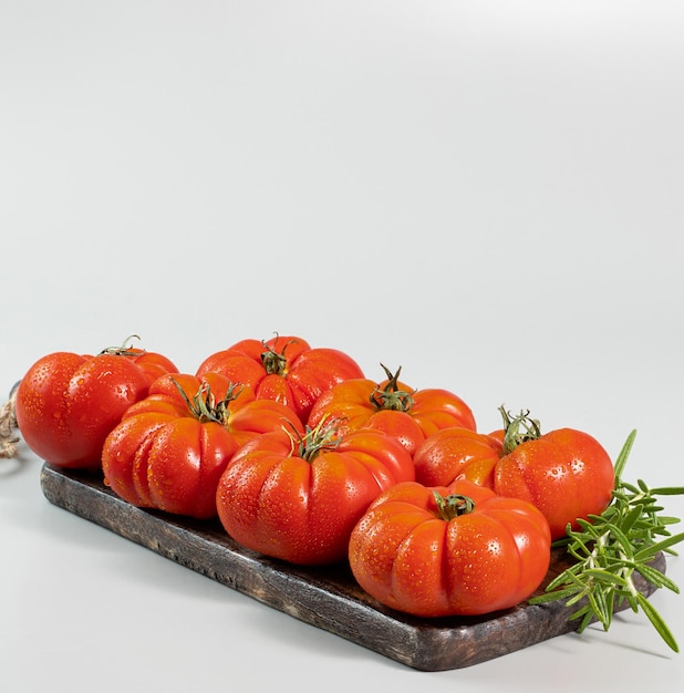 Een groep Costoluto grote tomaten en rozemarijn op een witte achtergrondruimte voor tekst