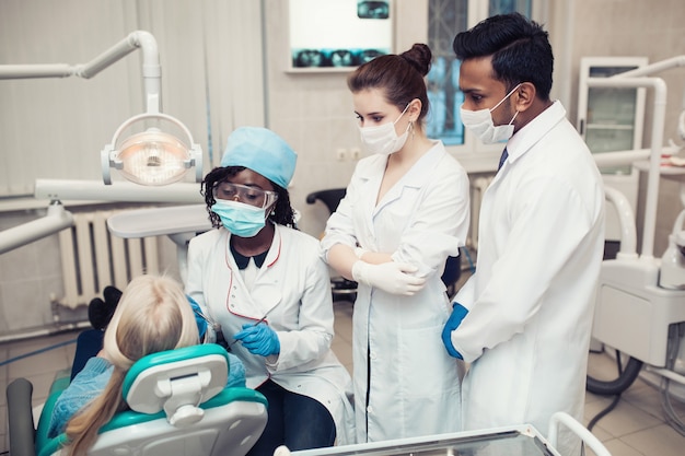 Een groep dermatologen van gemengd ras observeert als professor het meisje dat een zwarte vrouw tanden geneest