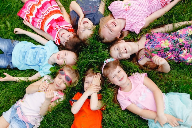 Een groep gelukkige kinderen jongens en meisjes die op een zonnige zomerdag in het park op het gras liggen.