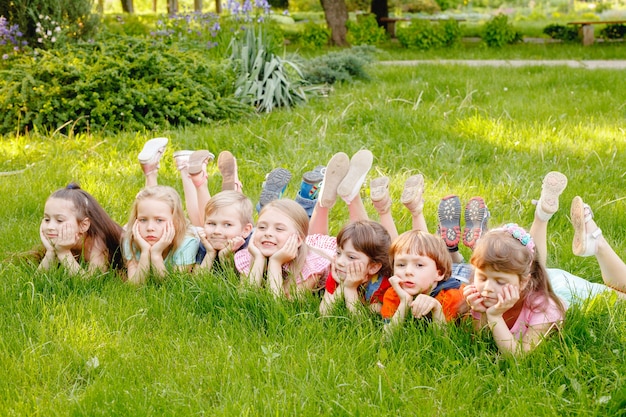 Een groep gelukkige kinderen jongens en meisjes die op een zonnige zomerdag in het park op het gras liggen.