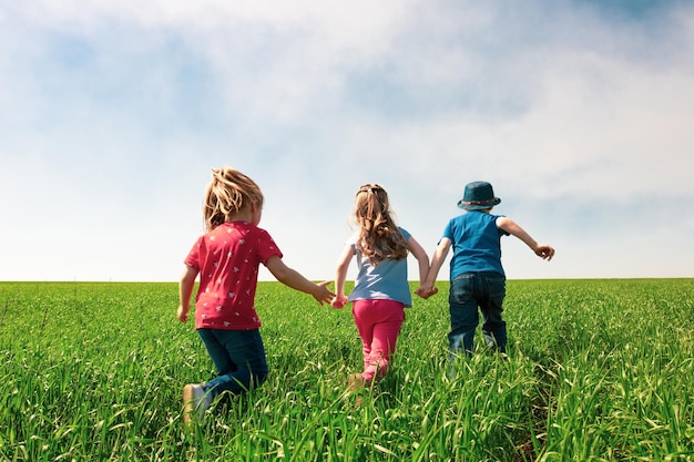 Een groep gelukkige kinderen van jongens en meisjes rennen in het park op het gras op een zonnige zomerdag Het concept van etnische vriendschap vrede vriendelijkheid jeugd