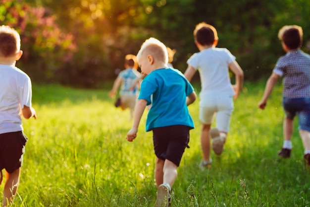 Een groep gelukkige kinderen van jongens en meisjes rennen op een zonnige zomerdag in het park op het gras.