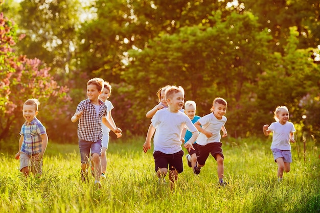 Een groep gelukkige kinderen van jongens en meisjes rennen op een zonnige zomerdag in het park op het gras.