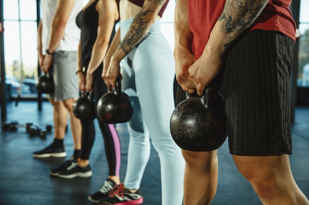 Een groep gespierde atleten die trainen in de sportschool. Gymnastiek, training, flexibiliteit voor fitnesstraining. Actieve en gezonde levensstijl, jeugd, bodybuilding. Close up van handen met gewichten opleiding.