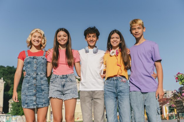 Een groep glimlachende vrienden, multiraciale tieners die kleurrijke t-shirts dragen en zich buiten knuffelen