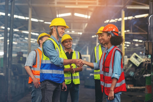 Een groep industriearbeiders en ingenieurs van verschillende rassen werken graag in een zware fabriek en staan samen met een aangename glimlach. portret