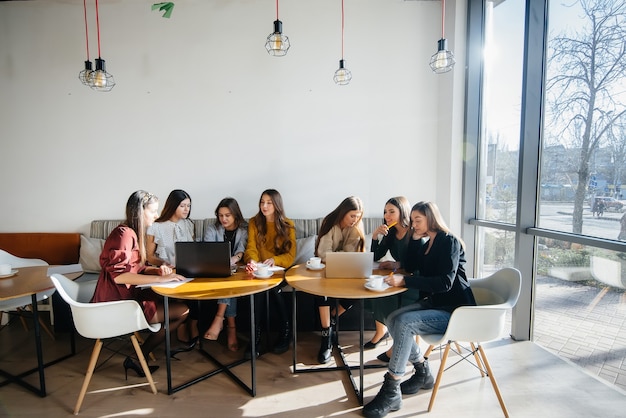 Een groep jonge meisjes zit in een kantoor achter computers en bespreekt projecten. Communicatie en training online.