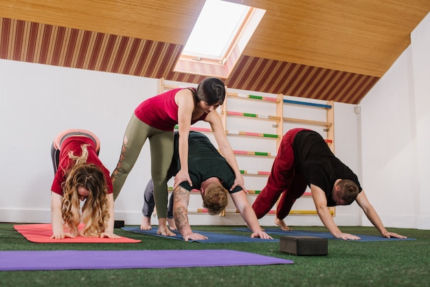Een groep jonge mensen die joga-oefeningen binnenshuis doen in de sportschool