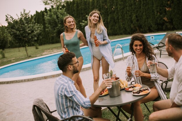 Een groep jonge mensen die met cider bij het zwembad in de tuin juichen.