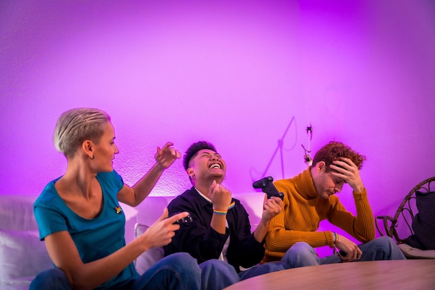 Een groep jonge vrienden die samen videogames spelen op de bank thuis, paarse led-man wint