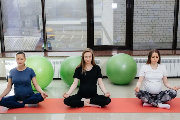 Een groep jonge zwangere meisjes doet yoga en sport op binnenmatten. Gezonde levensstijl