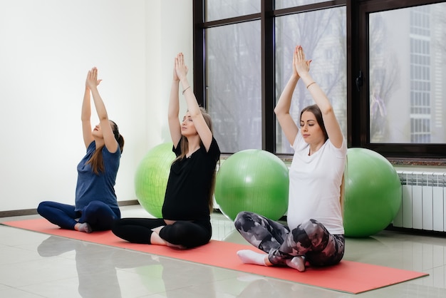 Een groep jonge zwangere meisjes doet yoga en sport op binnenmatten. Gezonde levensstijl