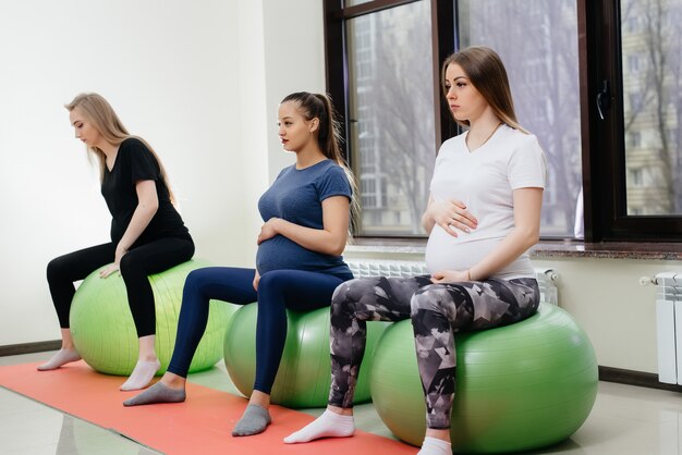 Een groep jonge zwangere moeders houdt zich bezig met Pilates en balsporten in een fitnessclub. Zwanger