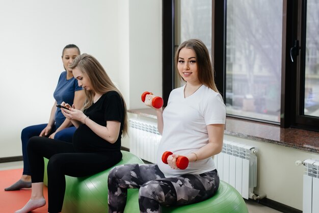 Een groep jonge zwangere moeders houdt zich bezig met Pilates en balsporten in een fitnessclub. Zwanger