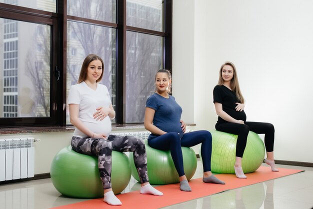 Een groep jonge zwangere moeders houdt zich bezig met pilates en balsporten in een fitnessclub.