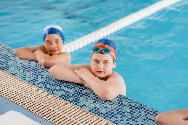 Een groep jongens en meisjes trainen en leren zwemmen in het zwembad met een instructeur. Ontwikkeling van kindersporten.