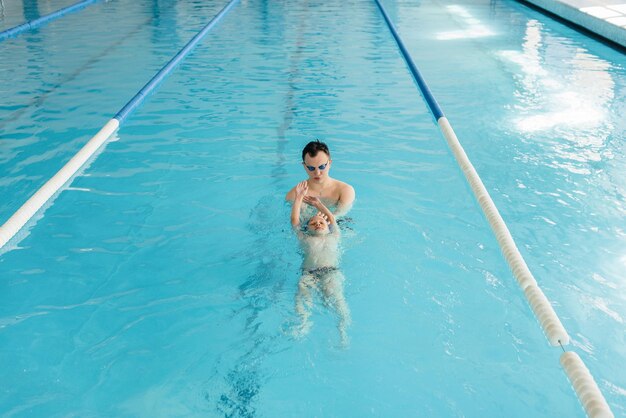 Een groep jongens en meisjes trainen en leren zwemmen in het zwembad met een instructeur. Ontwikkeling van kindersporten.