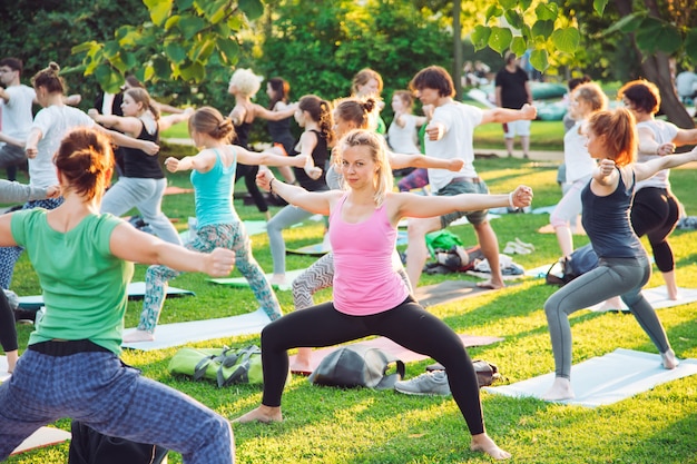 Een groep jongeren doet yoga in het park bij zonsondergang.