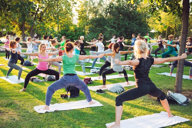 Een groep jongeren doet yoga in het park bij zonsondergang.