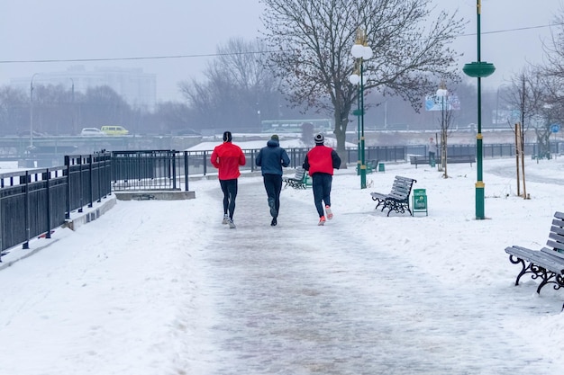 Een groep mannelijke atleten gaat 's ochtends hardlopen in een winterpark