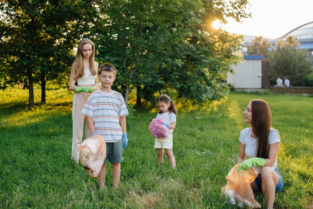 Een groep meisjes met kinderen bij zonsondergang houdt zich bezig met het ophalen van afval in het park. Milieuzorg, recycling.