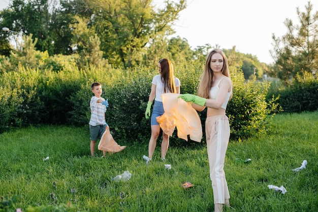 Een groep meisjes met kinderen bij zonsondergang houdt zich bezig met het ophalen van afval in het park. Milieuzorg, recycling.