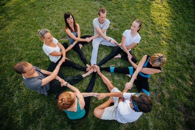 Een groep mensen doet yoga in een cirkel in de open lucht tijdens zonsondergang. Gezonde levensstijl, meditatie en wellness.