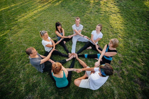 Een groep mensen doet yoga in een cirkel in de open lucht tijdens zonsondergang