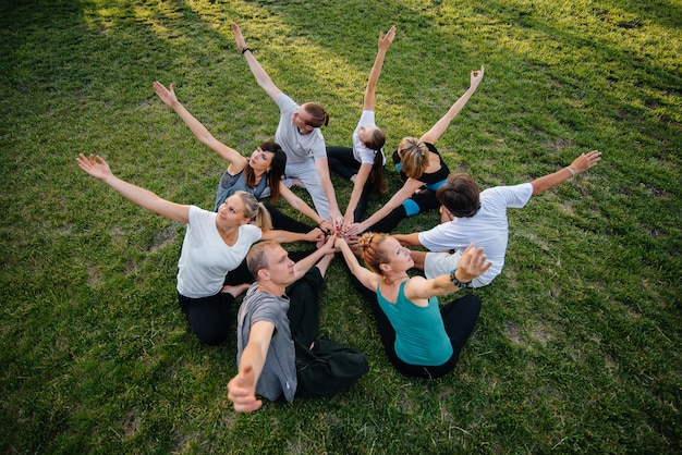 Een groep mensen doet yoga in een cirkel in de open lucht tijdens zonsondergang