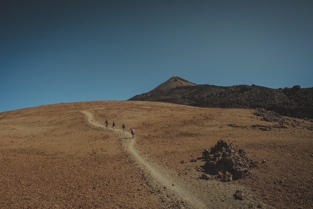 Een groep mensen loopt over een pad dat naar een berg stijgt