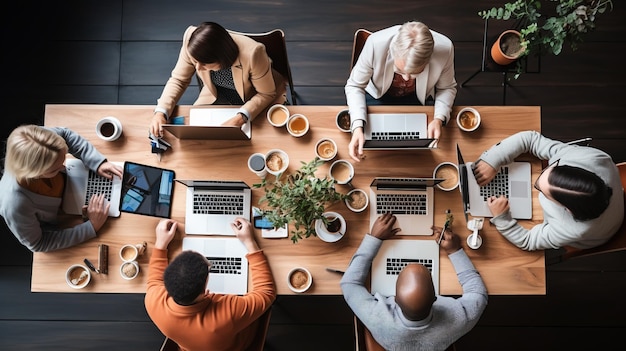 Een groep mensen van verschillende etnische groepen zit rond een tafel en werkt aan hun laptop