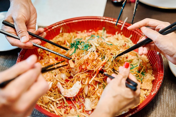 Foto een groep mensen viert het chinese nieuwjaar met een lohei of welvaart gooien met eetstokjes